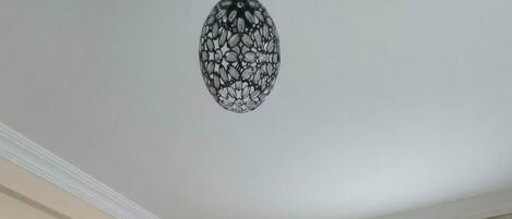 Una sala de estar con dos sofás, un tapete estampado, un reloj de pared y una lámpara decorativa en el techo.