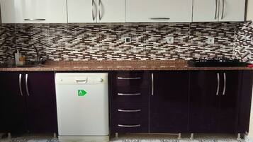 A kitchen with white cabinets, a patterned backsplash, and a tiled floor.