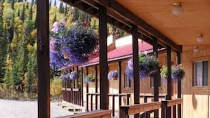 A wooden cabin with a covered porch, wooden railings, and hanging flower baskets.