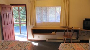 A room with two beds, a desk with a chair, a television, and a window with curtains.