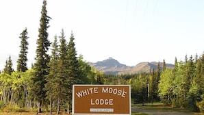A sign for White Moose Lodge with a mountainous backdrop.
