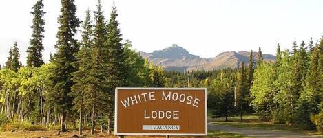 A sign for White Moose Lodge with a mountainous backdrop.