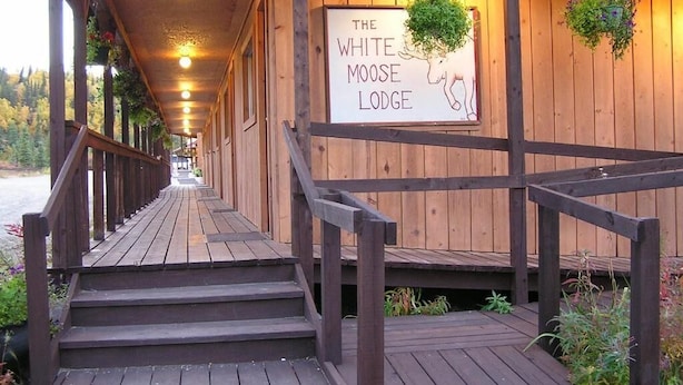 A wooden covered walkway leading to a lodge with a sign reading "The White Moose Lodge".