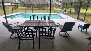 Un patio cubierto con piscina, mobiliario exterior y ventilador de techo.