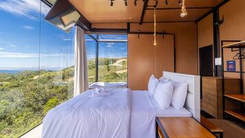 A bedroom with a large bed, a wooden headboard, and a view of a hilly landscape.
