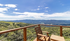 Una terraza de madera con un banco que da a un paisaje montañoso.