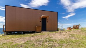 A modern, single-story building with a large door and a small porch area. - Cabana romântica perto de Florianópolis VST038 (Anitápolis)