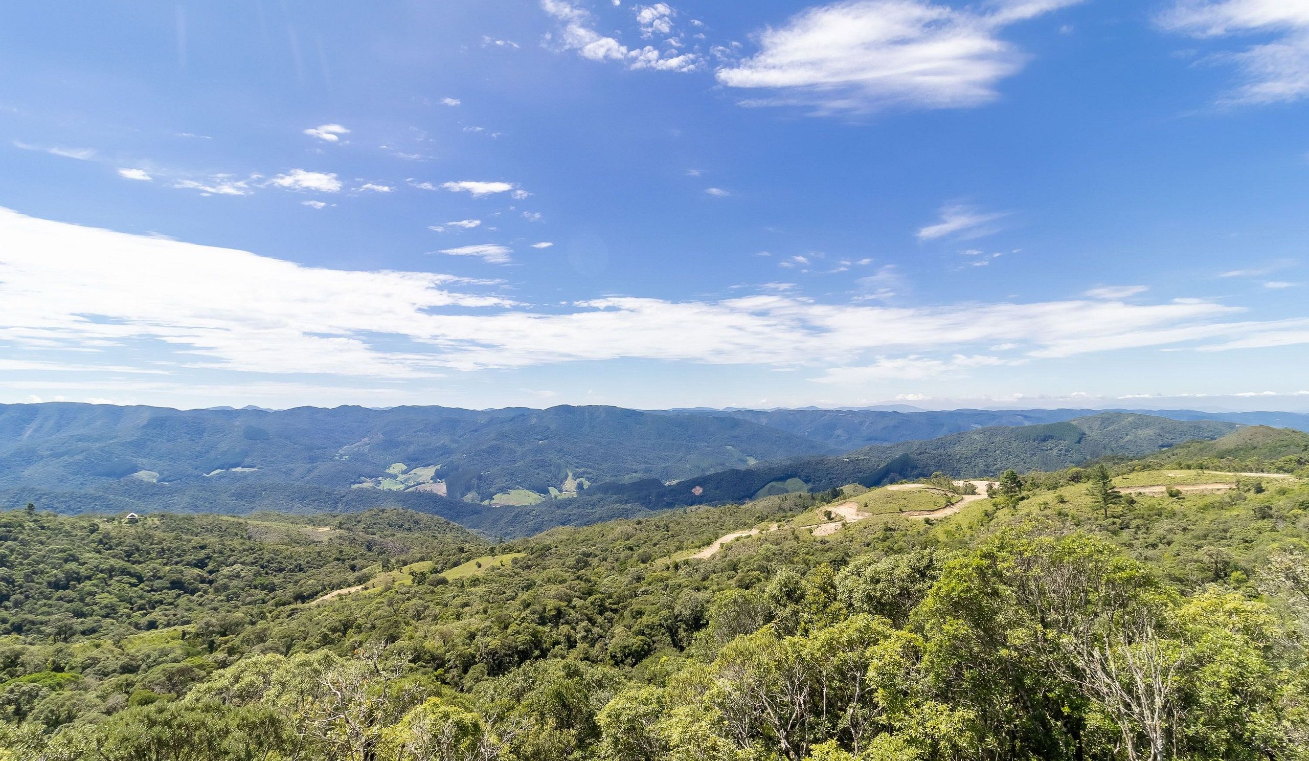A panoramic view of a mountainous landscape with dense greenery and a clear sky.