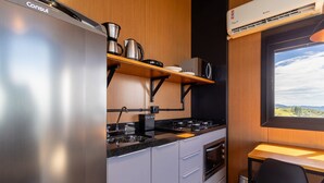 A compact kitchen with a built-in refrigerator, a stove, and a microwave. - Cabana romântica perto de Florianópolis VST038 (Anitápolis)