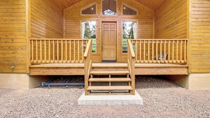 Eine Holzhütte mit Veranda, einer Treppe zum Eingang und einem Kiesgrundstück.