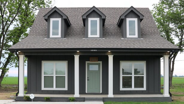 A two-story house with a dark exterior, large windows, and a front porch. - Roll Mill, Steel Bend Guest Houses: Roll Mill (Osceola)