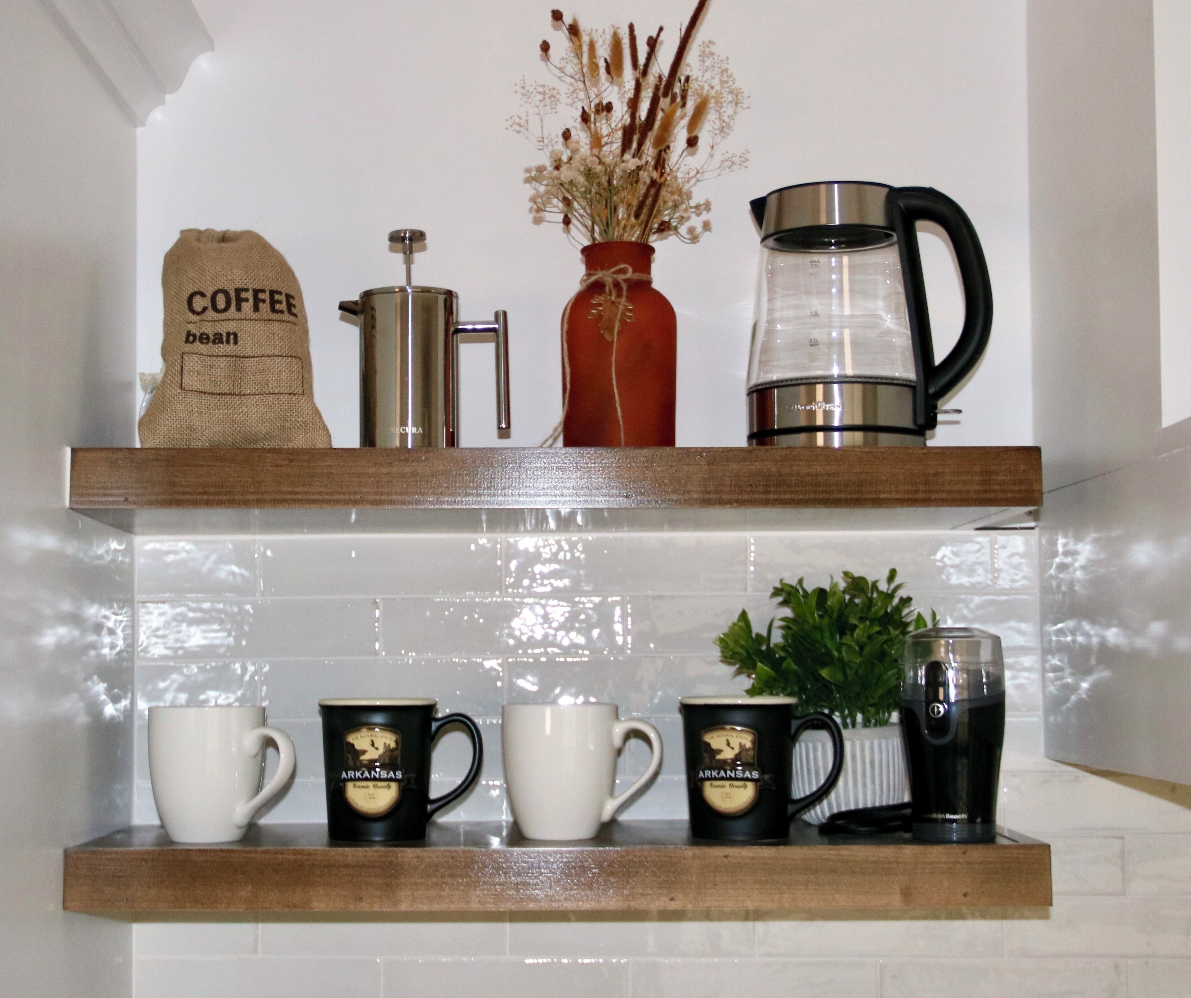 Una repisa en la cocina con equipo para preparar café, un saco de granos de café y tazas.