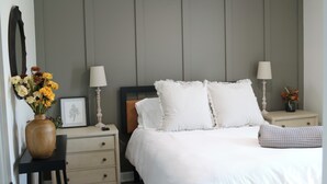 Ein Schlafzimmer mit einem Bett, zwei Nachttischen, einem Schminktisch und einem Spiegel.