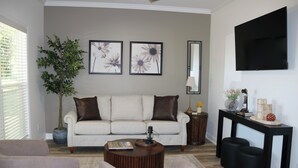 Ein Wohnzimmer mit einer Couch, einem Couchtisch und einem an der Wand montierten Fernseher.
