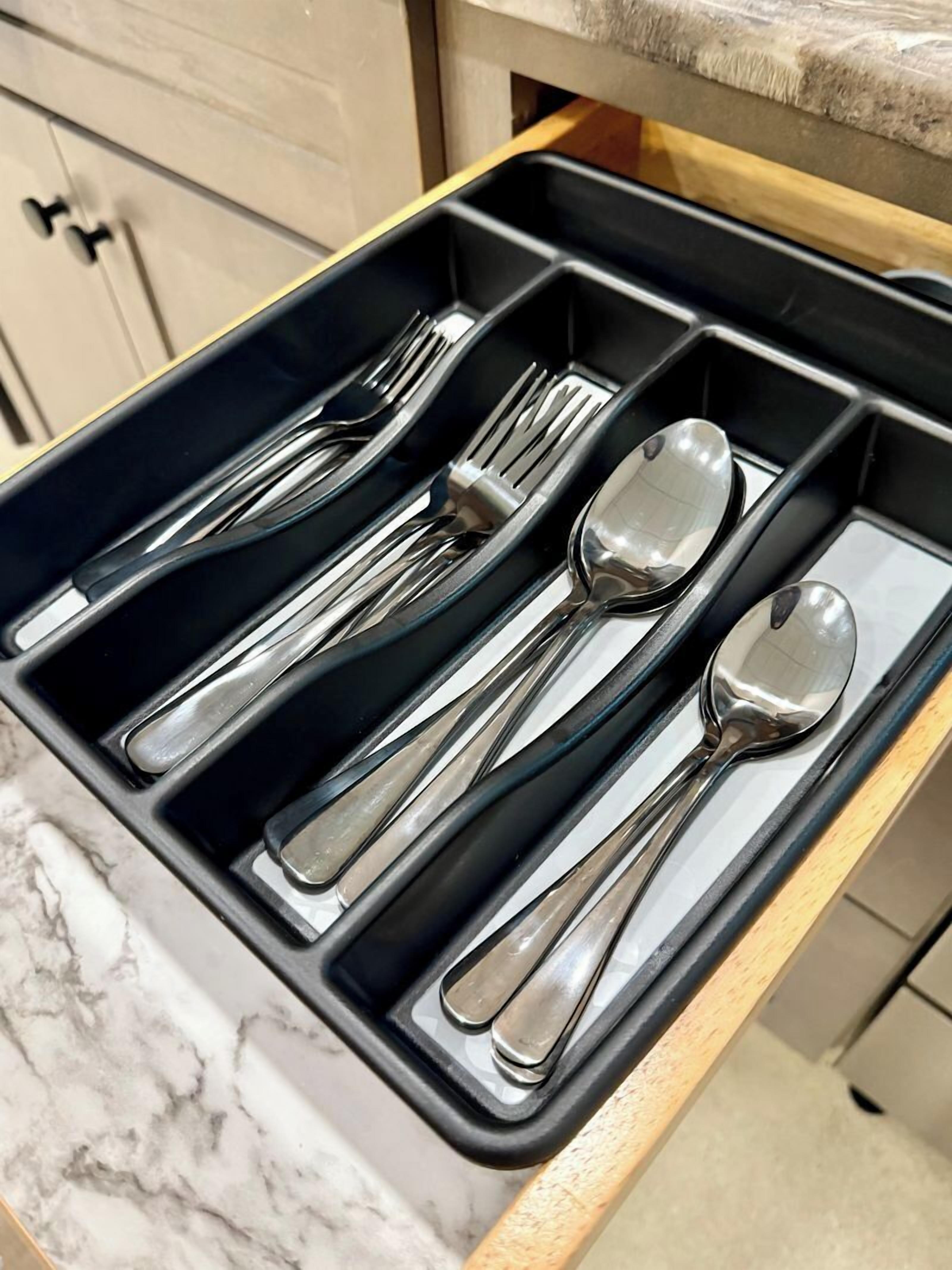 A drawer with multiple compartments containing various utensils.
