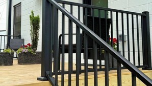 A modern building with a wooden deck and a black metal railing.
