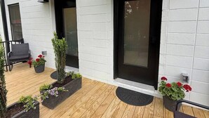 A modern house with a wooden deck, black-framed windows, and a black door.