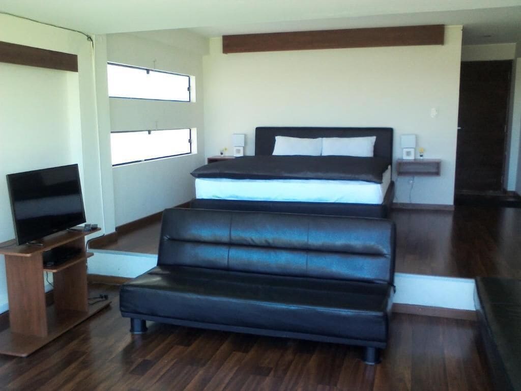 A bedroom with a bed, a TV, and a wooden entertainment unit.