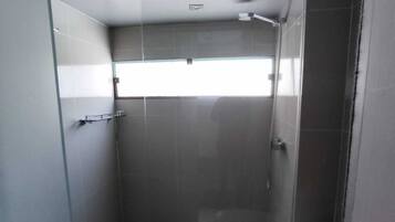 Un baño pequeño y moderno con cabina de ducha de vidrio, inodoro y ventana que proporciona luz natural.