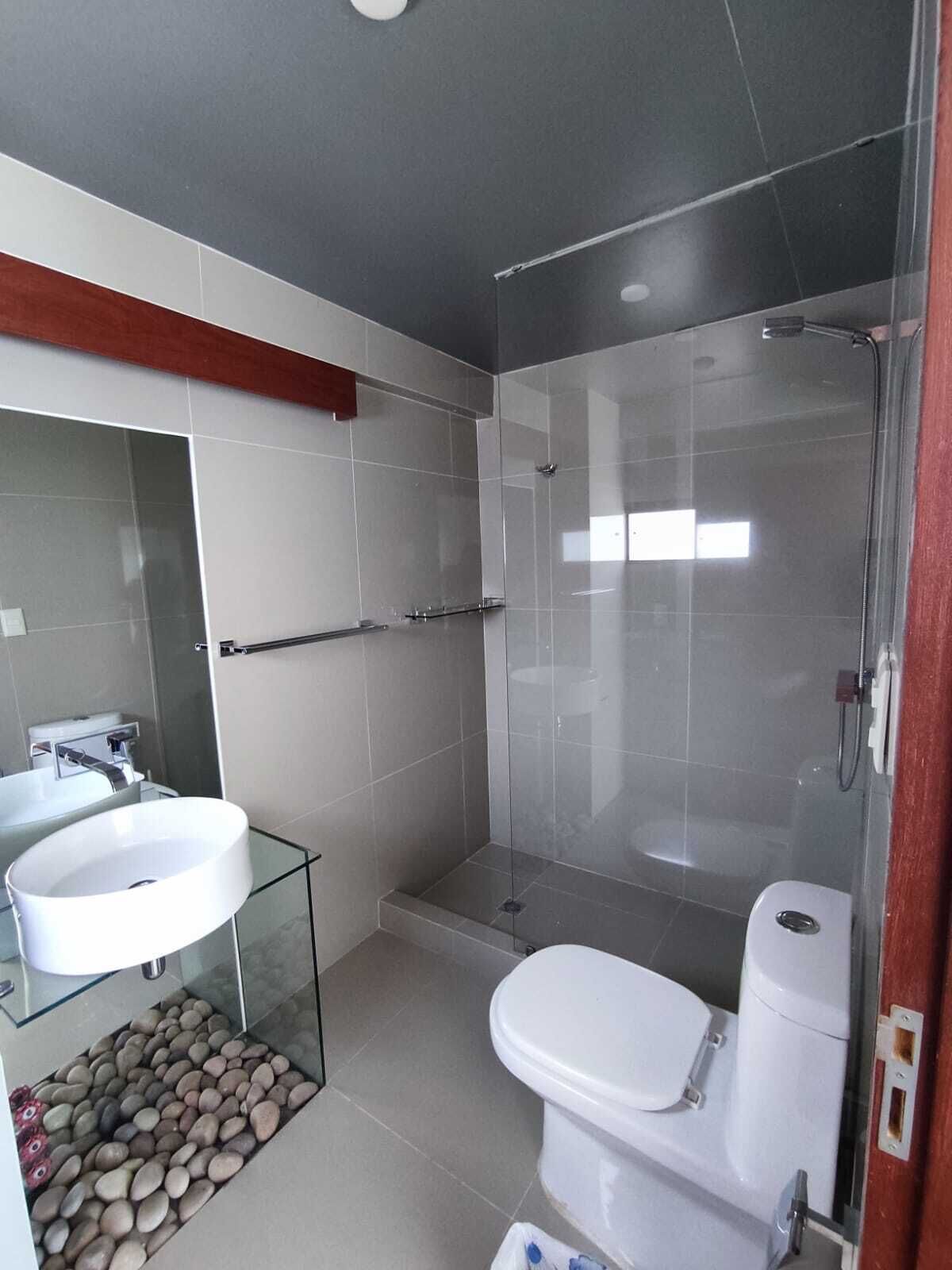 Un bany modern amb un lavabo tancat per vidre, un vàter blanc i una cabina de bany amb vidre.