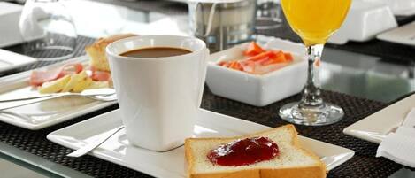 A breakfast setting with a cup of coffee, a glass of orange juice, toast with jam, and a plate of eggs and bacon.