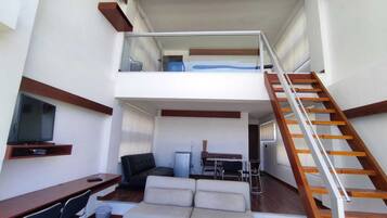 Un interior moderno con zona de estar tipo loft, un comedor y una escalera.