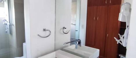 A modern bathroom with two sinks, a glass shower enclosure, and a wooden vanity.