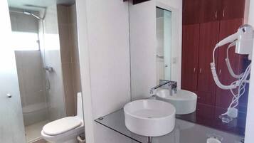 Un baño moderno con lavamanos de vidrio, inodoro y ducha.