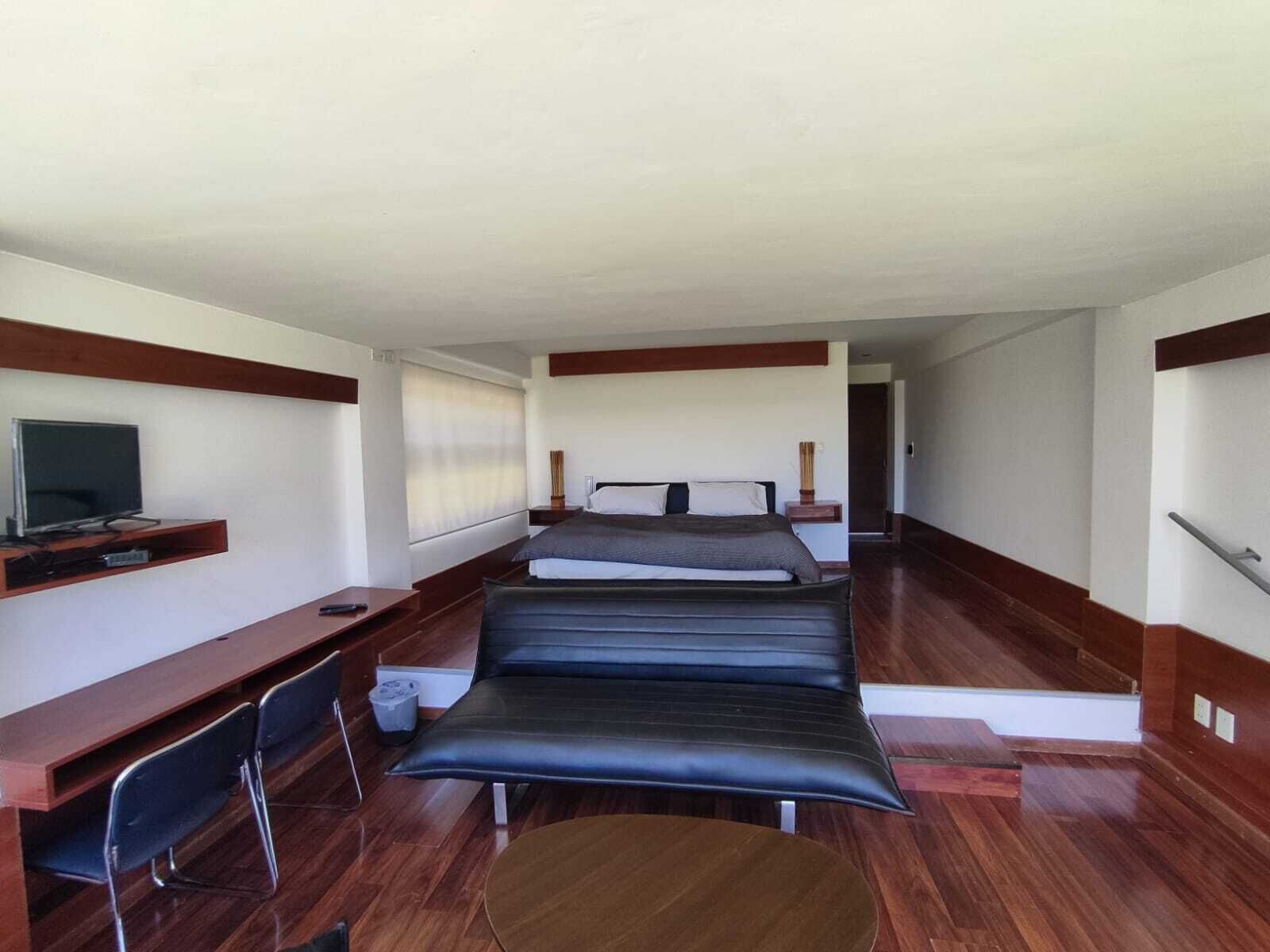 A modern hotel room with a bed, a desk, a chair, and a television.