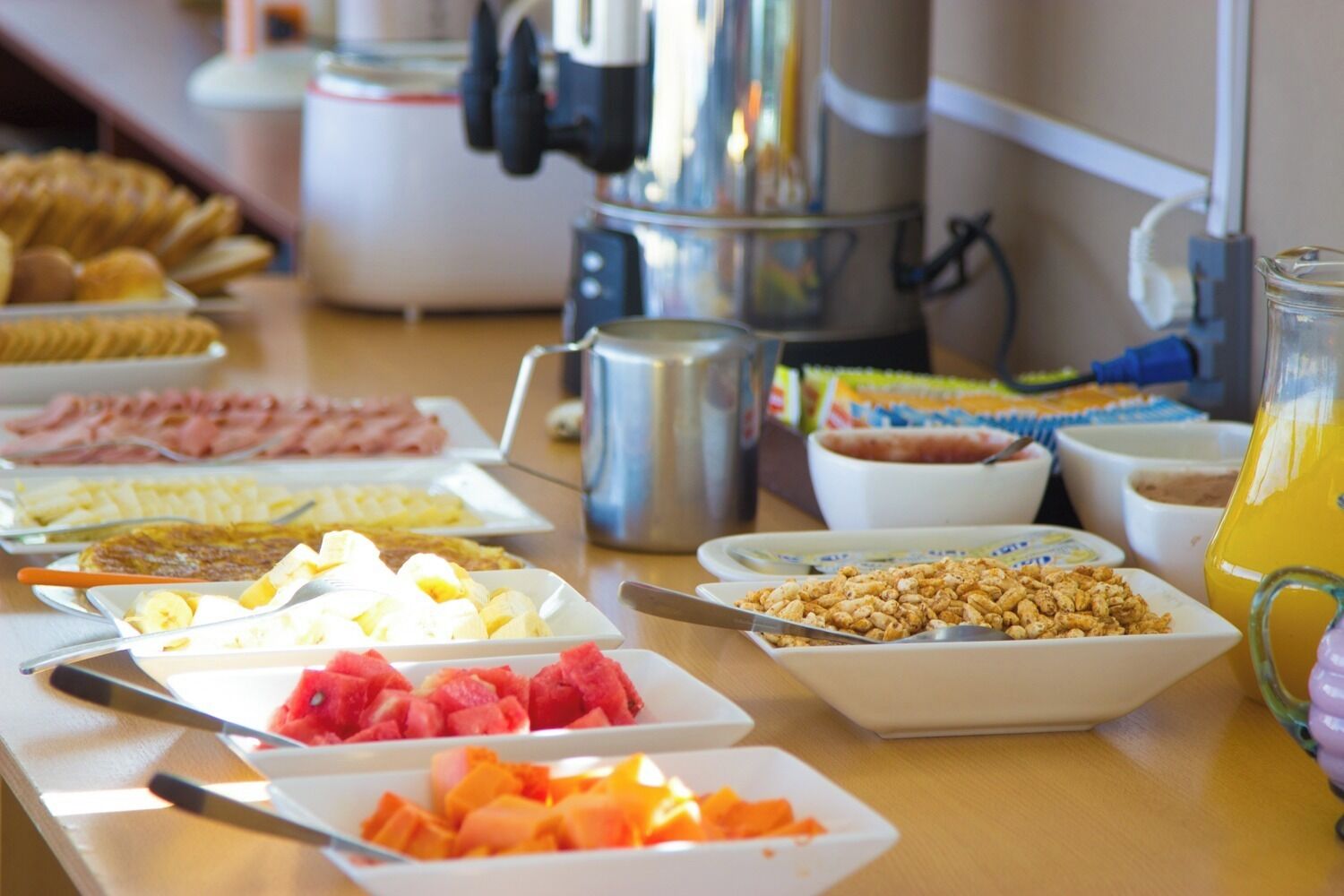 Ein Buffet mit verschiedenen Speisen, darunter Obst, Getreideprodukte und Getränke.