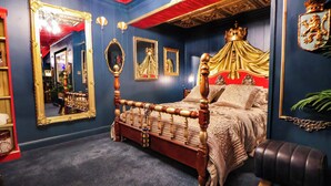 Un dormitorio con cama con dosel, espejos ornamentados y techo rojo.