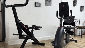 Ein Heimfitnessstudio mit Crosstrainer und Hometrainer, eine Wand mit motivierenden Sprüchen und ein Holzboden.