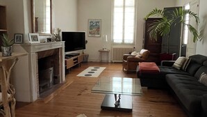 A living room with a fireplace, a television, a sofa, and a coffee table. - Charming house with swimming pool (Bordeaux)