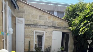 A stone building with a tiled patio, a table with chairs, and a cactus plant. - Charming house with swimming pool (Bordeaux)