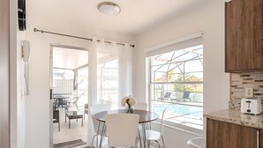 Una cocina moderna con comedor, ventanas amplias y vistas a una piscina.