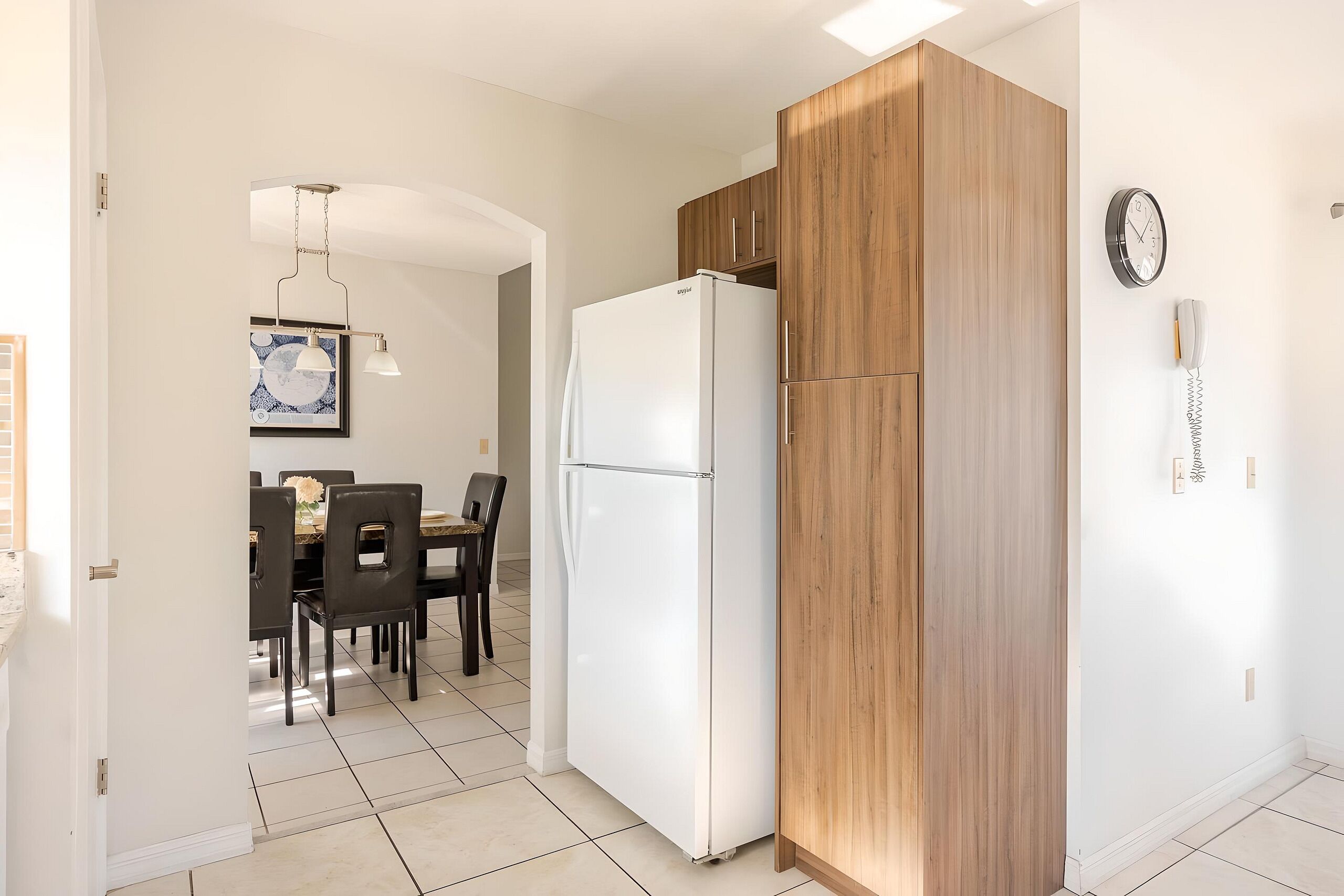 Una cocina moderna con un refrigerador blanco, gabinetes de madera y un comedor con mesa y sillas.