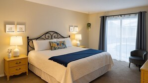 Une chambre d’hôtel bien aménagée, avec un grand lit, deux tables de chevet avec des lampes, une chaise et une fenêtre avec des rideaux.