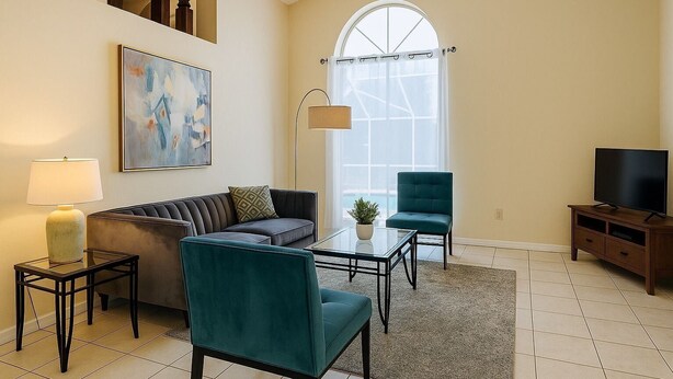 Un salon comprenant un canapé, deux fauteuils, une table basse, une lampe, un meuble pour la télévision et un tableau accroché au mur.
