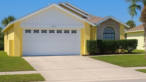 Une maison à deux étages avec un garage, une façade en pierre et une pelouse bien entretenue.