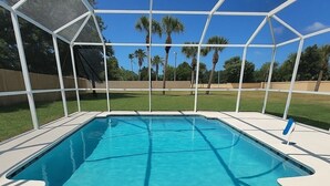 Une piscine rectangulaire à l’eau d’un bleu limpide, entourée d’une plage blanche et d’une clôture de sécurité transparente.