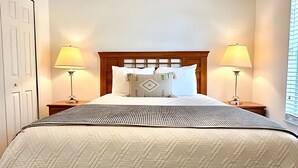 A neatly made bed with a patterned bedspread, two bedside lamps, and a wooden headboard.