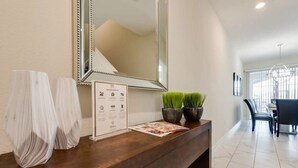 A reception desk with a mirror, two potted plants, and a welcome brochure.