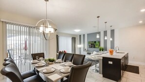 A modern dining area with a round table, black chairs, and a central light fixture.