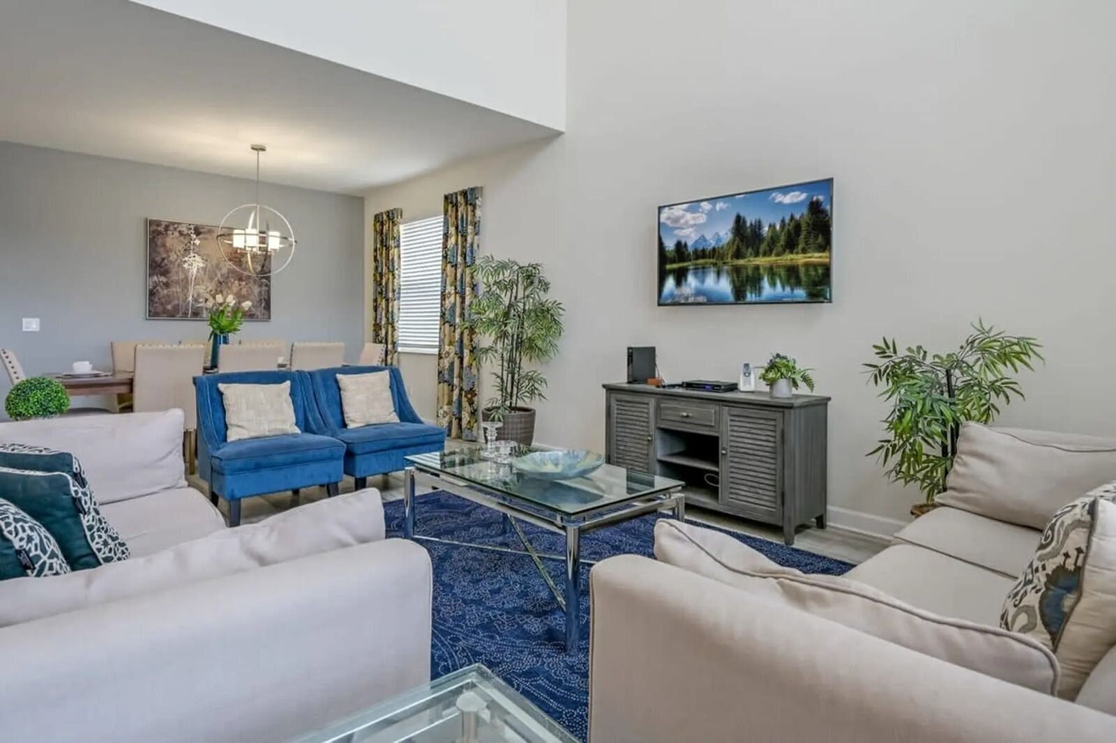 A modern living room with a glass coffee table, two sofas, a TV, and a painting on the wall.