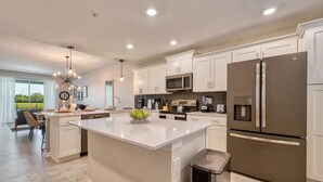 Una cocina moderna con armarios blancos, electrodomésticos de acero inoxidable y una isla central.