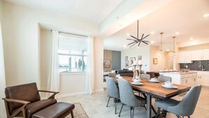 A modern dining area with a wooden table set for four, surrounded by grey chairs.