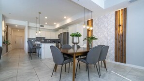 A modern kitchen with white cabinets, a central island, and pendant lighting. - 2BR Storey Lake | Sleeps 7 | 10min Disney (Kissimmee)