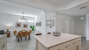 A modern kitchen with a central island, dining area with chairs, and a chandelier. - 3BR/2BA Apartment – 10 Min to Disney Parks! (Kissimmee)