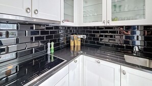 A modern kitchen with white cabinets, black backsplash, and stainless steel appliances. - Maison 't Blyhuis - De Panne (De Panne)