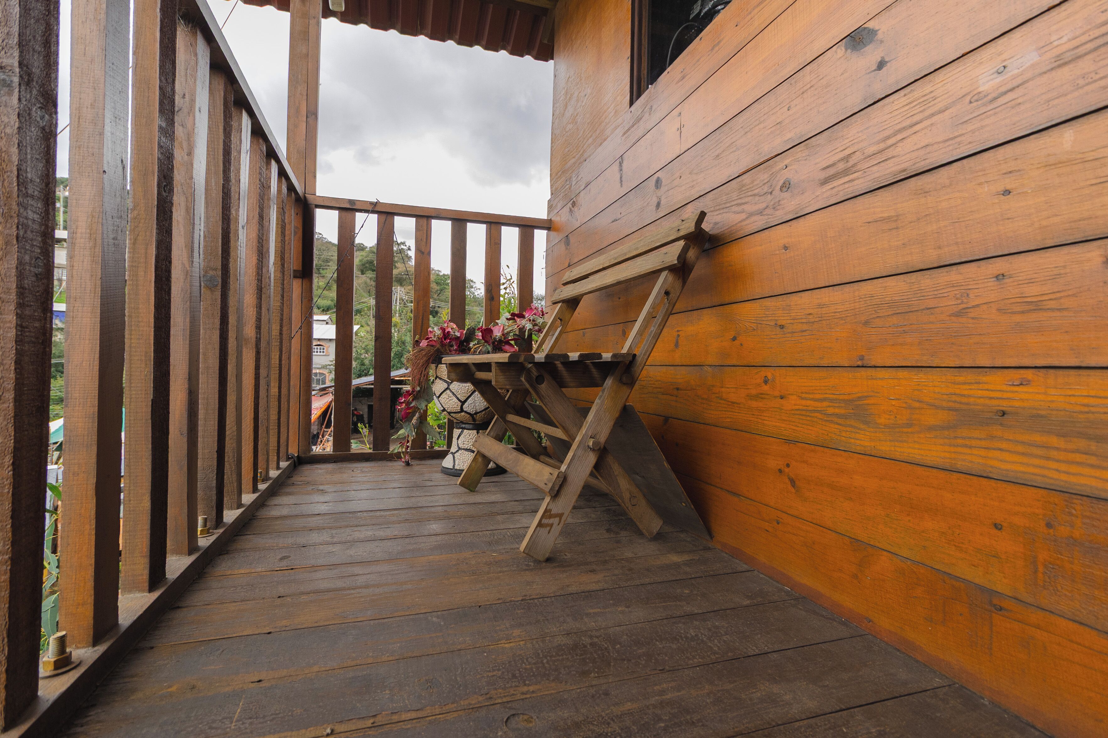 A wooden deck with a wooden bench and a small table with flowers.